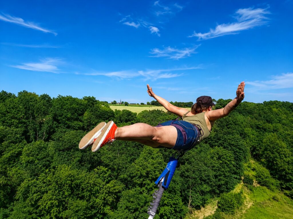 Personne équipée pour un saut à l’élastique contemplant le paysage pendant l’expérience